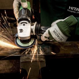 worker holds a grinder to metal as sparks fly