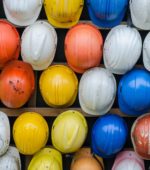 many hard hats lined up in yellows, oranges, reds and whites