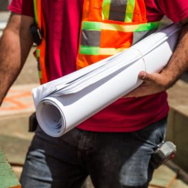 construction manager holds rolled up plans