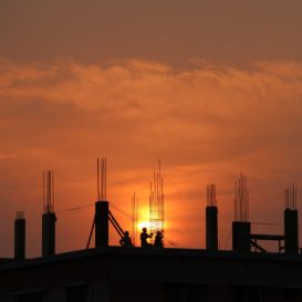 the sun sets behind the partially built structure of a commercial building