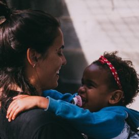 daycare teacher holds smiling toddler girl
