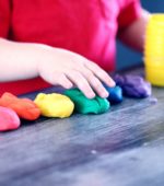 preschooler has a rainbow selection of play dough to play with