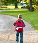 six year old walking down gravel path wearing backpack