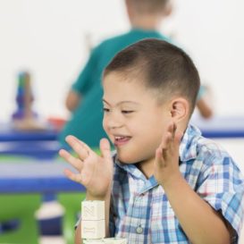 boy with down syndrome is clapping after finishing task with teacher