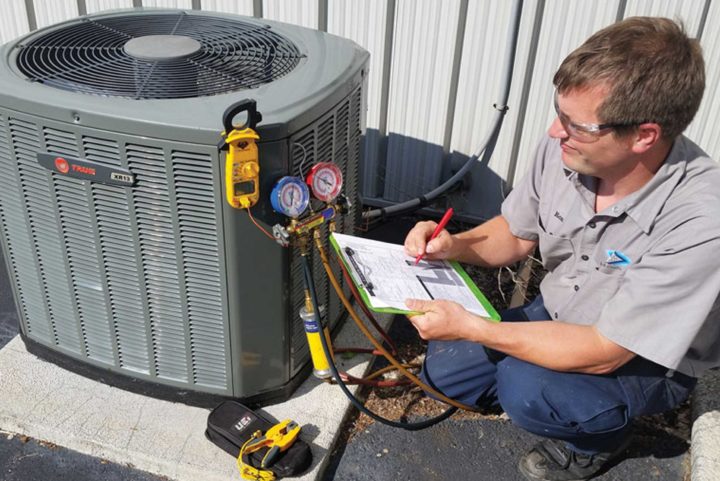 Heating and Air Conditioning Mechanic checking gauges on air conditioning unit