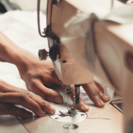 hands pushing fabric through a sewing machine
