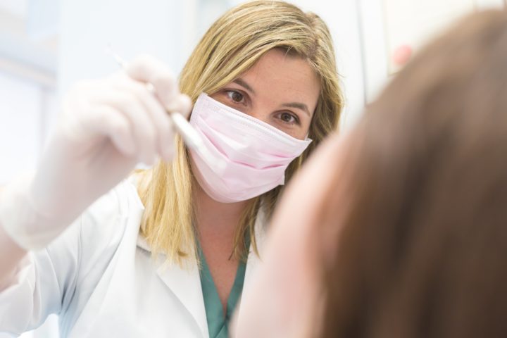 Dental Hygienist holds tool while examining patient