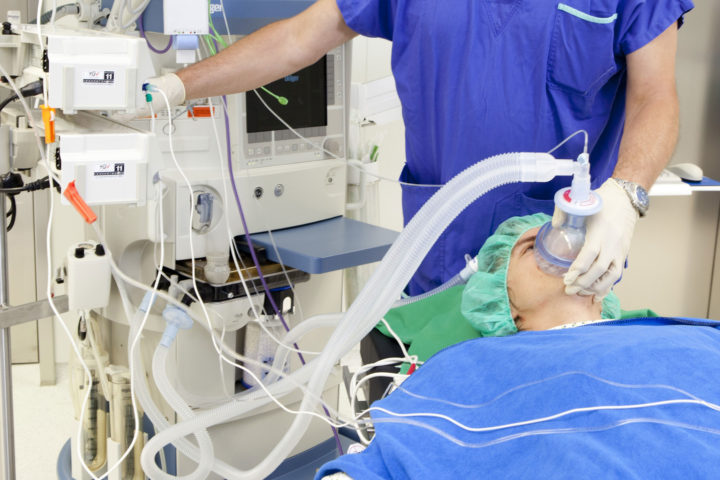 Respiratory Therapist monitors equipment while tending to a patient