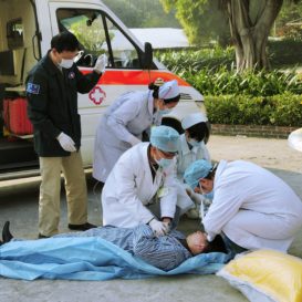 paramedics attend to a sick patient on the ground outside
