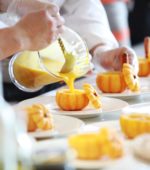 sous chefs pouring soup into miniature pumpkins on plates