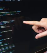 finger pointing at code on a computer monitor