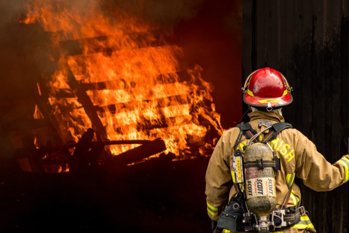 fire fighter stands in front of burning building